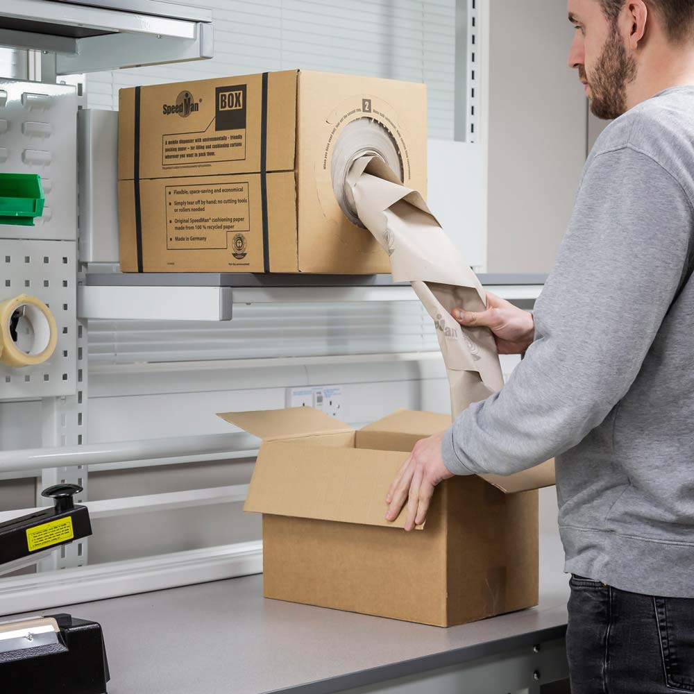 Paper Void Fill being used to pack a box on a packing bench